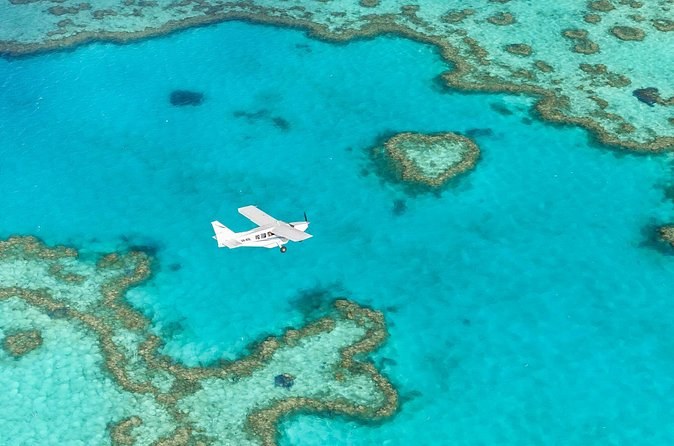 Heart Reef from the air, a small plane flying past the heart-shaped coral in turquoise water
