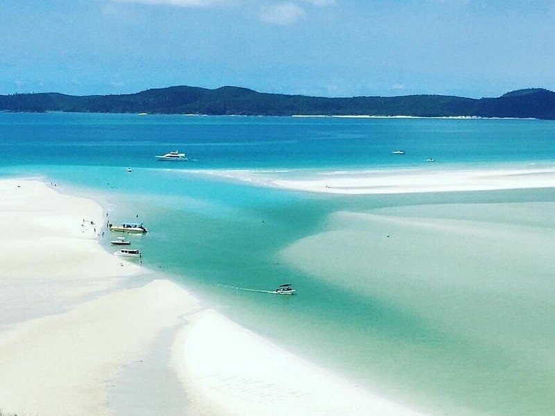 Hill Inlet from the air at low water, ribbons of white sand curling through turquoise channels, boats anchored along the bars