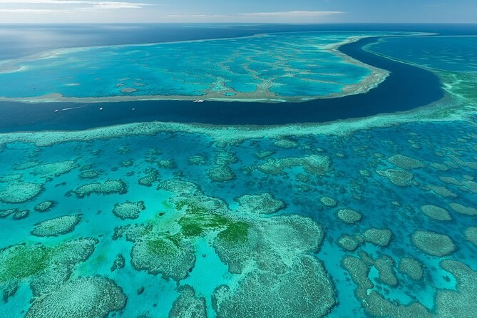 Reef flats and a winding deep-water channel seen from the air, far offshore